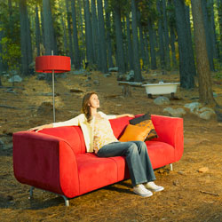 Frau sitzt auf rotem Sofa im Wald